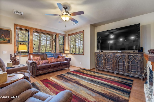 living room featuring a ceiling fan, visible vents, and wood finished floors