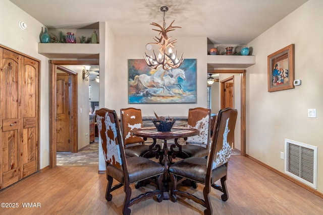 dining area featuring light wood-type flooring, an inviting chandelier, baseboards, and visible vents