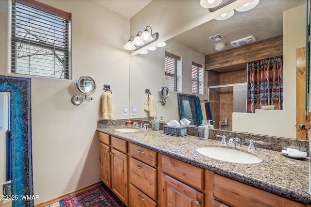 bathroom with a shower with shower door, visible vents, a sink, and double vanity