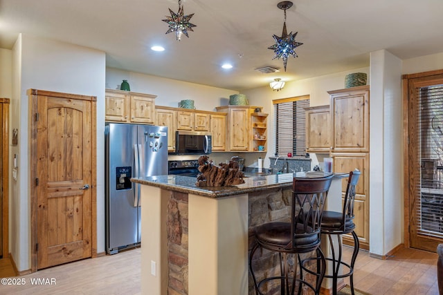 kitchen with a breakfast bar, appliances with stainless steel finishes, a center island, dark stone counters, and open shelves