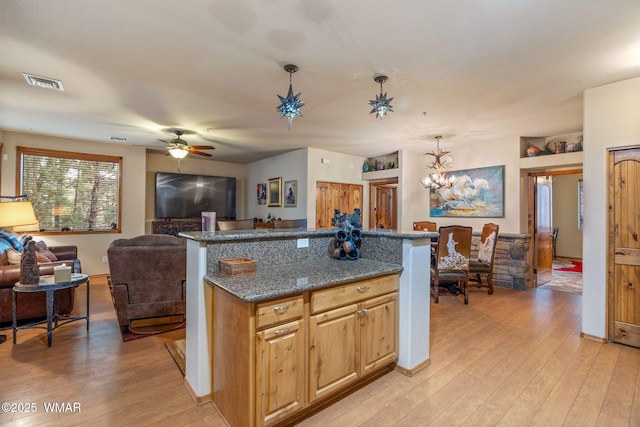 kitchen with open floor plan, a kitchen island, visible vents, and pendant lighting