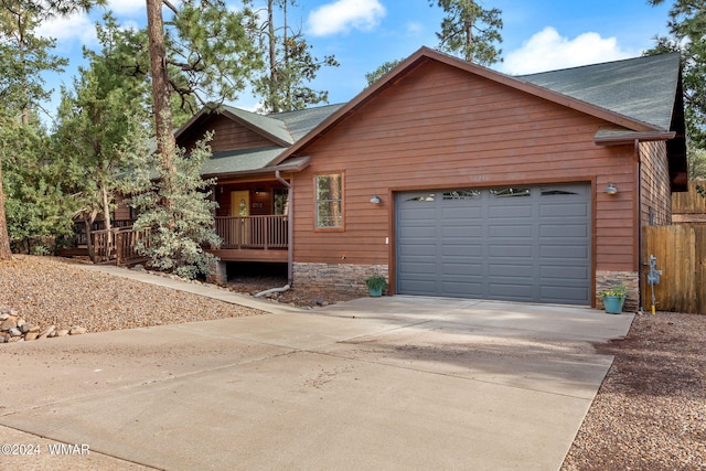 rustic home with a garage, driveway, a porch, and stone siding