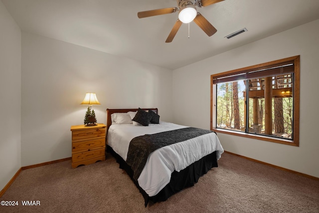 carpeted bedroom featuring a ceiling fan, visible vents, and baseboards