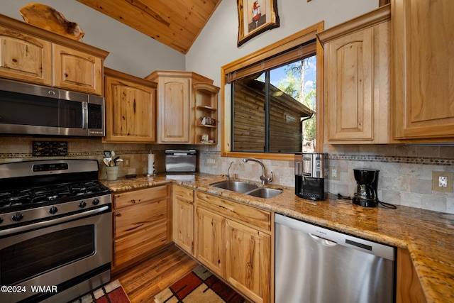 kitchen featuring stainless steel appliances, vaulted ceiling, a sink, and decorative backsplash