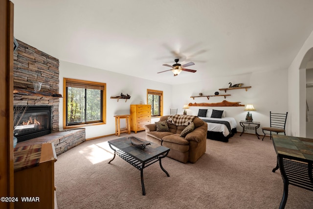 living area with a ceiling fan, carpet, and a stone fireplace