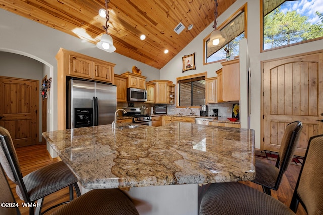 kitchen featuring a breakfast bar, arched walkways, stainless steel appliances, wood ceiling, and a sink