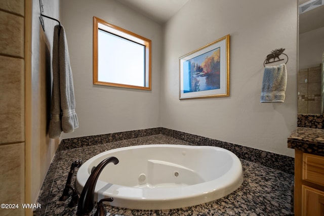 full bath with visible vents, a jetted tub, and vanity