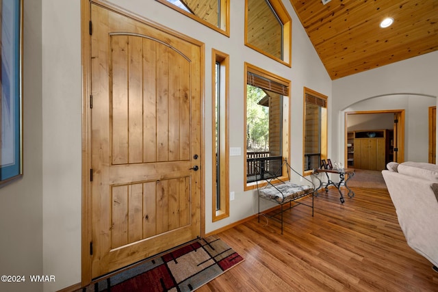 entrance foyer featuring arched walkways, high vaulted ceiling, wooden ceiling, wood finished floors, and baseboards