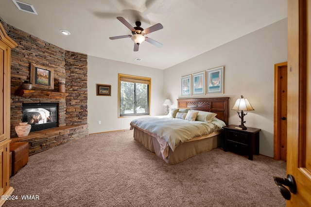 bedroom with ceiling fan, a stone fireplace, carpet flooring, and visible vents