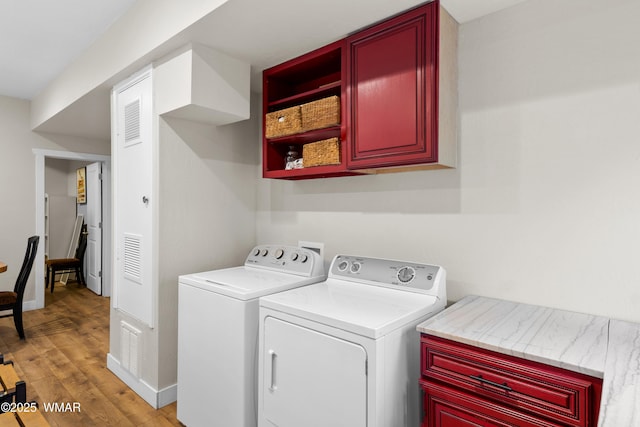 washroom with cabinet space, visible vents, washing machine and dryer, and light wood finished floors