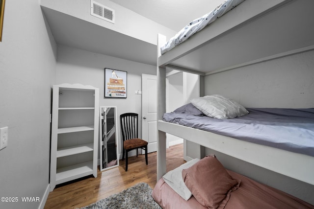 bedroom featuring visible vents, baseboards, and wood finished floors