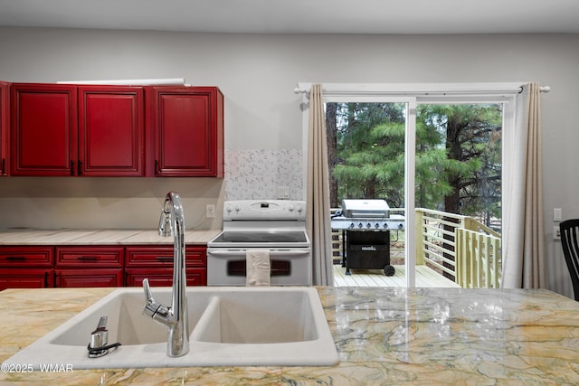 kitchen featuring a sink, dark brown cabinets, white range with electric cooktop, and light countertops