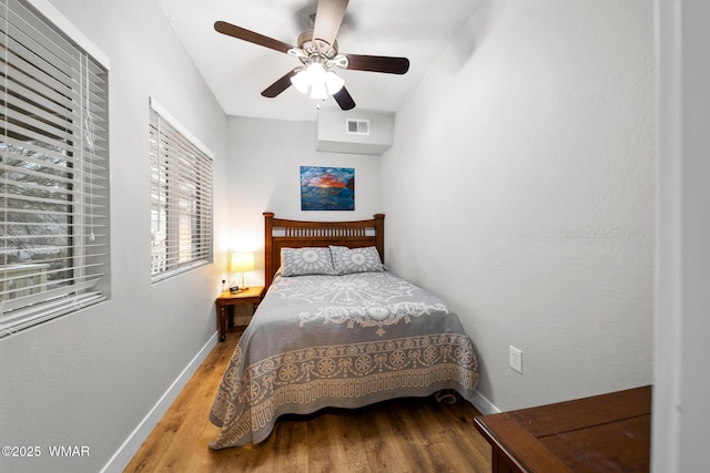 bedroom with baseboards, a ceiling fan, wood finished floors, and visible vents