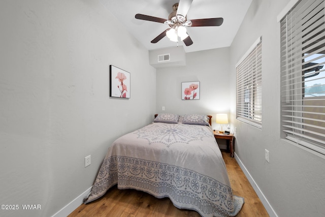 bedroom with baseboards, a ceiling fan, wood finished floors, and visible vents