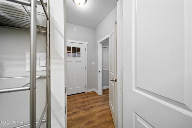 corridor with baseboards and wood finished floors
