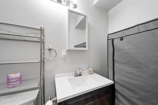bathroom with vanity, a textured wall, and toilet
