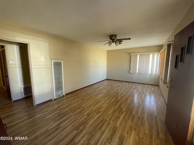 interior space with a ceiling fan, dark wood-style flooring, visible vents, and baseboards