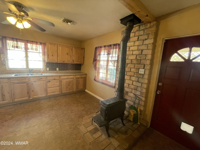 kitchen featuring visible vents, a wood stove, a sink, light countertops, and backsplash