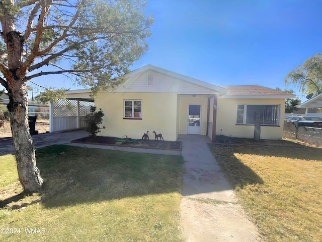 view of front of house with a front lawn, roof with shingles, fence, and stucco siding