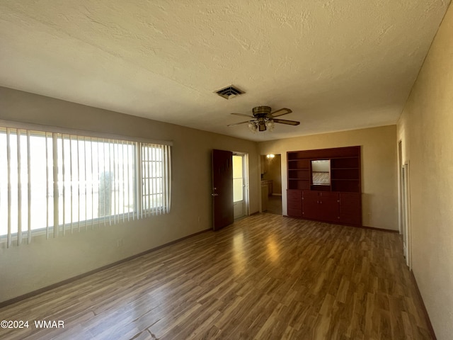 unfurnished room with dark wood-type flooring, visible vents, ceiling fan, and a textured ceiling