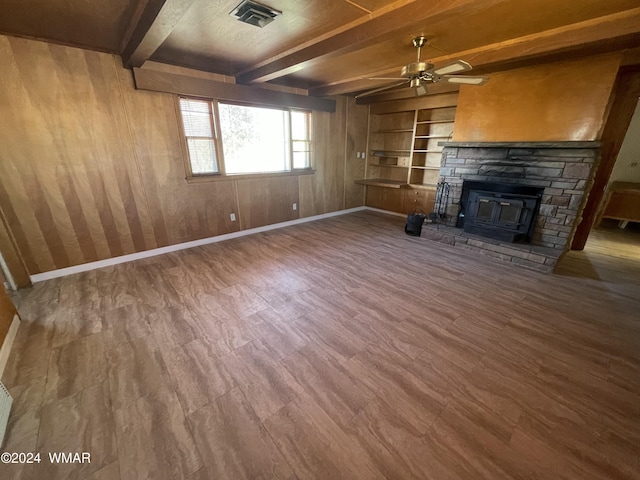 unfurnished living room with beam ceiling, visible vents, a ceiling fan, a stone fireplace, and baseboards