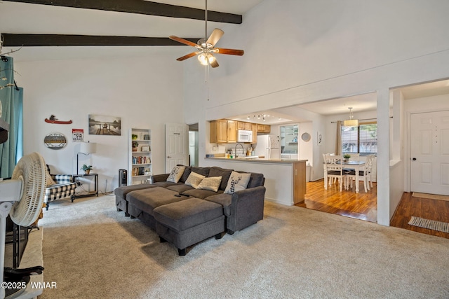 living area featuring light wood finished floors, ceiling fan, beam ceiling, and light colored carpet