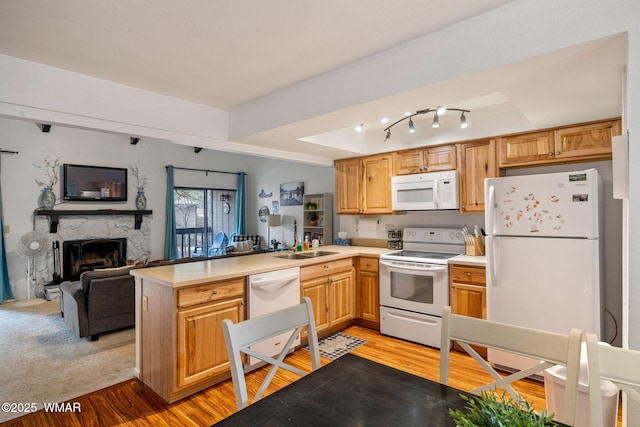 kitchen featuring a fireplace, light wood finished floors, light countertops, white appliances, and a peninsula