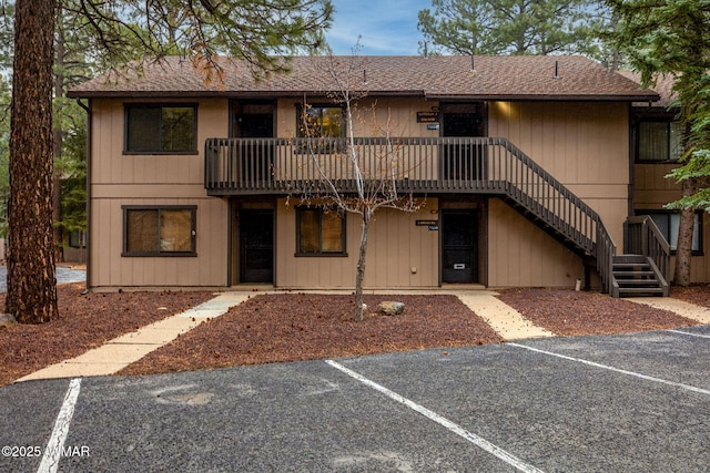 view of building exterior with uncovered parking and stairway