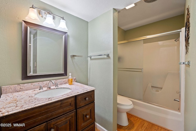 full bathroom with toilet, shower / bath combination with glass door, wood finished floors, and vanity