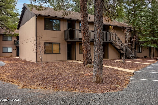 view of building exterior with uncovered parking and stairway