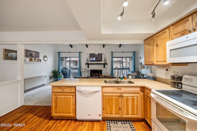 kitchen with white appliances, a raised ceiling, open floor plan, a peninsula, and a sink