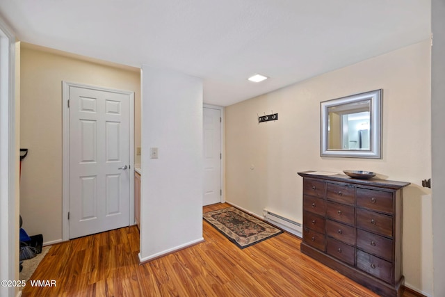 bedroom featuring a baseboard radiator, baseboards, and light wood-style flooring