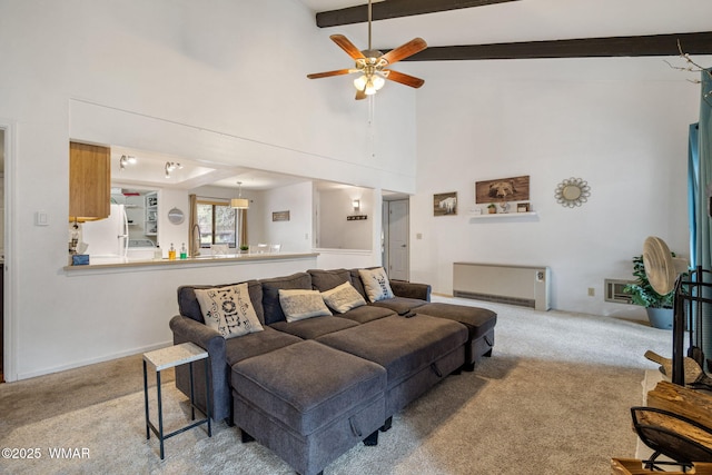 carpeted living area with a sink, ceiling fan, a high ceiling, and beamed ceiling