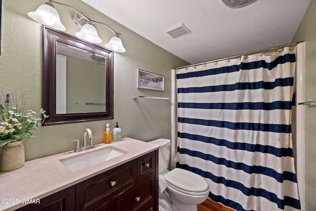 full bath featuring a textured wall, curtained shower, toilet, vanity, and visible vents