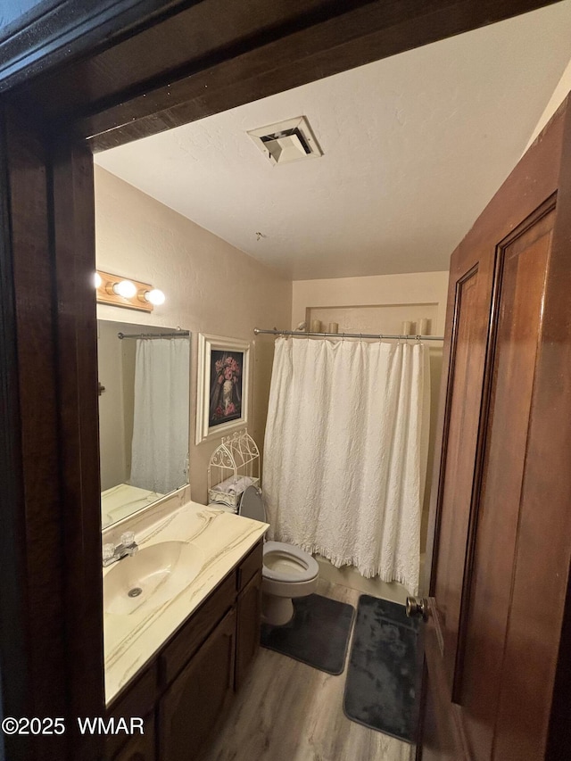 bathroom featuring vanity, toilet, wood finished floors, and visible vents