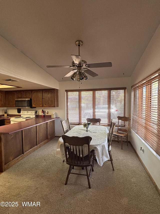 dining area featuring light carpet, a healthy amount of sunlight, a ceiling fan, and lofted ceiling