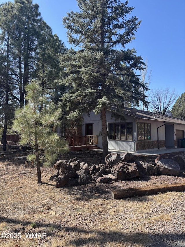 rear view of house with a garage, a wooden deck, and a sunroom