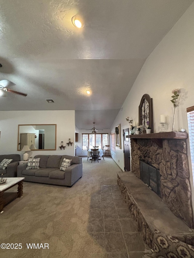 living room with visible vents, a ceiling fan, a textured ceiling, a fireplace, and carpet flooring