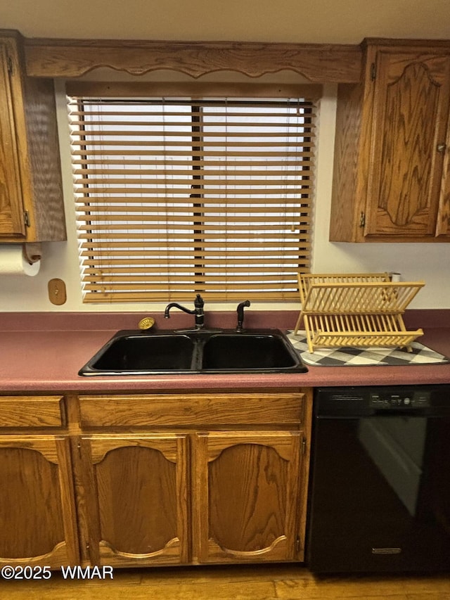 kitchen with black dishwasher, brown cabinets, and a sink