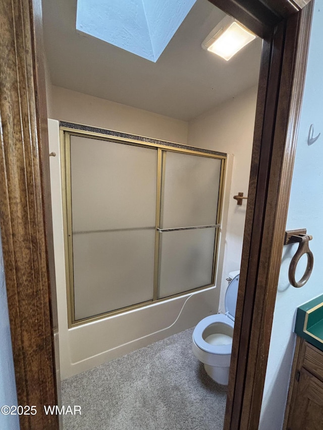 full bath featuring a skylight, toilet, and bath / shower combo with glass door