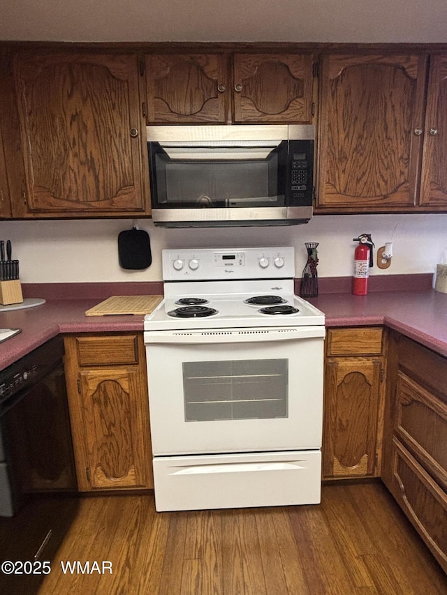 kitchen with white range with electric stovetop, stainless steel microwave, dark wood finished floors, and black dishwasher