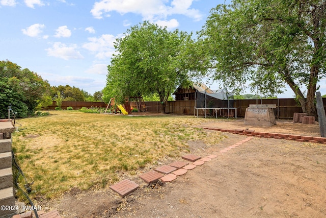 view of yard featuring a fenced backyard, a trampoline, a playground, and a patio