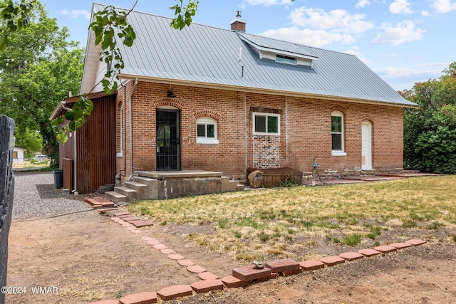 view of front of home with a chimney, metal roof, and brick siding