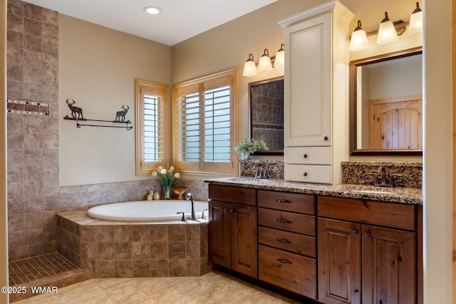 full bath with double vanity, tile patterned flooring, a garden tub, and a sink