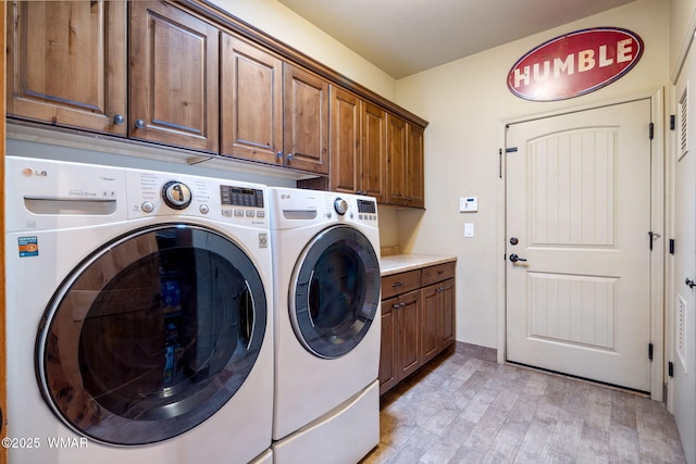 washroom with cabinet space, light wood-style floors, and washing machine and clothes dryer