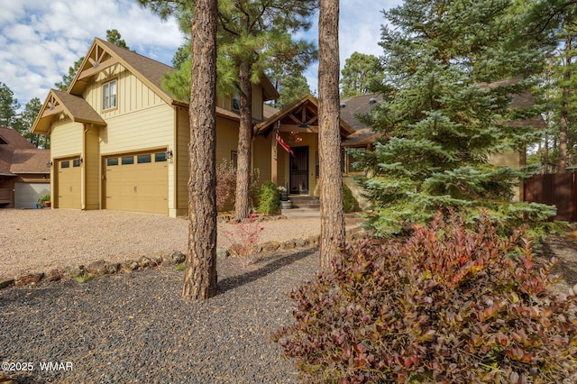 view of front of property featuring fence, gravel driveway, a shingled roof, a garage, and board and batten siding