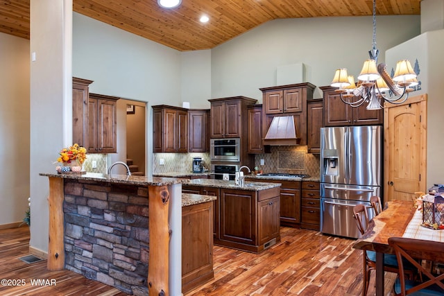 kitchen with wood finished floors, wood ceiling, premium range hood, and stainless steel appliances