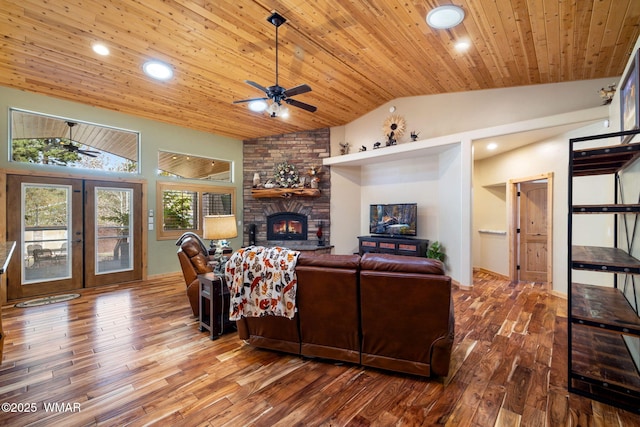 living area with wood finished floors, french doors, a stone fireplace, wood ceiling, and vaulted ceiling