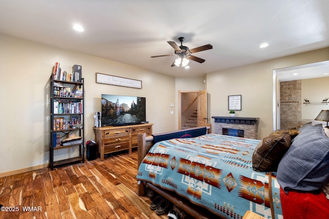 bedroom featuring recessed lighting, wood finished floors, a fireplace, and ceiling fan