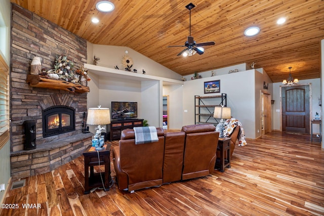 living area featuring visible vents, wood finished floors, a fireplace, and vaulted ceiling